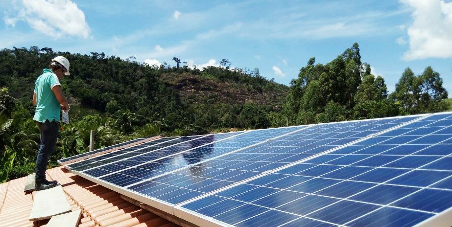 Técnico da SOS Energia Solar sobre o telhado, conferindo os módulos instalados